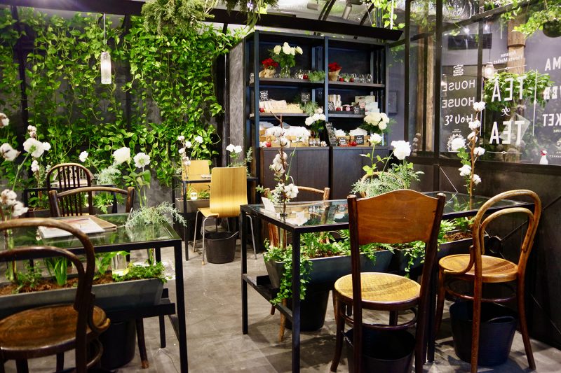 表参道greenhouseの店内。植物に囲まれた温室のような空間に並ぶテーブル席