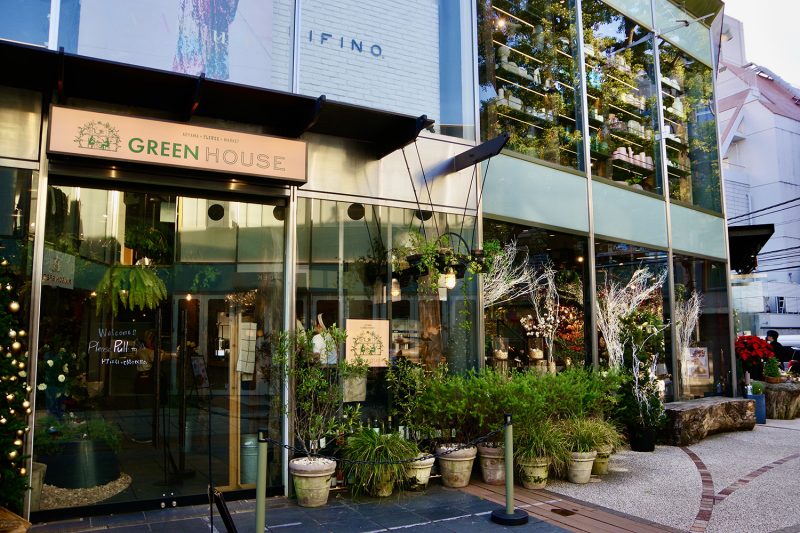 表参道のカフェ「GREEN HOUSE」の外観。ガラス張りの建物と植栽に囲まれた入口